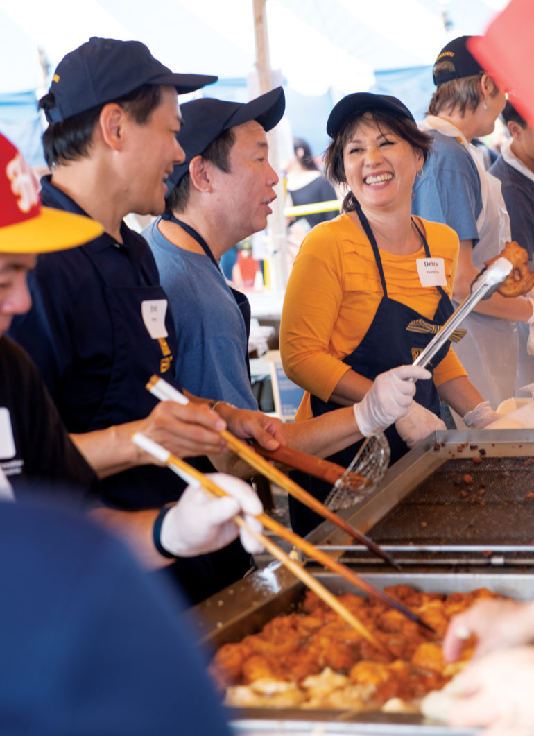 Class of 1984 alumni Eric Wong, Bob Yee and Debra Young Otsu enjoy each other’s company while working a shift making malasadas.